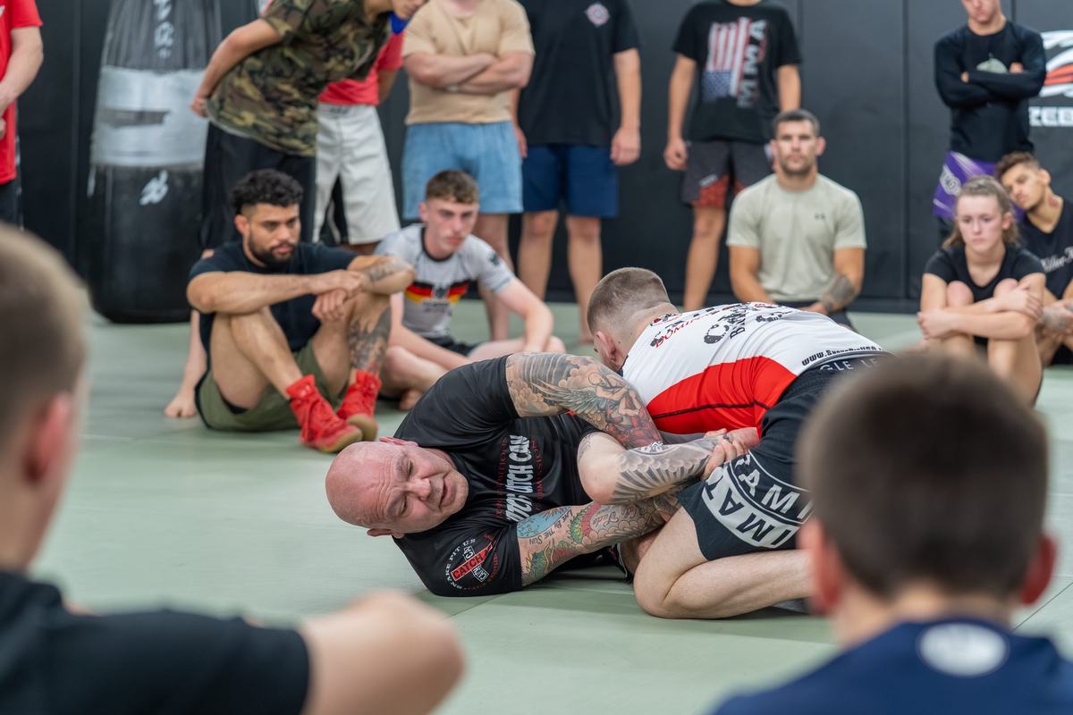 Coach teaching a grappling detail to a full class